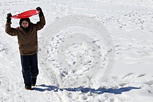 Young boy walks with tobogganing on the head