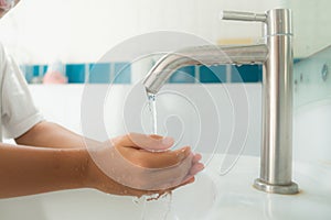 Young boy wash his hand by water from faucet