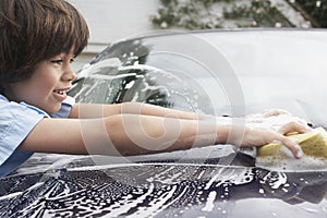 Young Boy Washing Car With Sponge