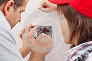 Young boy watches as his father installs an electrical wall sock