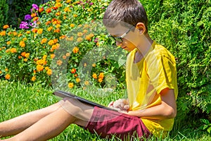 Young boy watching movies on tablet in a park alone