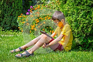Young boy watching movies on tablet in a park alone