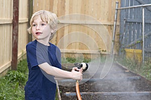 Young boy watering a suburban garden