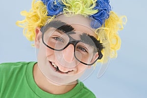 Young boy wearing clown wig and fake nose smiling