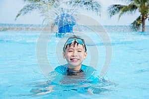 Young boy wearing goggles swimming in swimming pool
