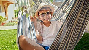 Young boy, wearing a hat, blissfully swaying in a hammock a true depiction of carefree vacation vibes