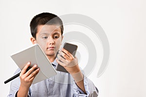 Young boy wearing his dads shirt pretending to be businessman with digital devices and pen. Childhood education, learning play