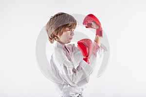 Young boy wearing karate kimono and bred boxing gloves concentrating