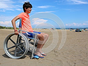 Young boy with wheelchair on the beach and shorts