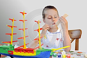 Young boy - woodcraft ship painting, focused photo