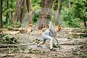 Young boy in the woods in a clearing with a wooden stick