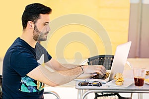Young boy working with his laptop from the outside terrace of a bar in Spain. Telecommuting, space for text, copyspace