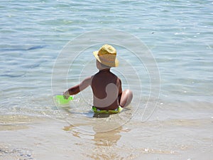 a young boy in a yellow hat playing with frisbees on a beach