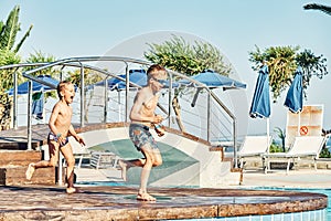 Young boys with bare torsos jumping into swimming pool