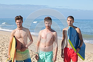Young boys carry bodyboards on shore