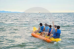 Young boys and girl riding on the banana boat on the sea in Pattaya, Thailand.