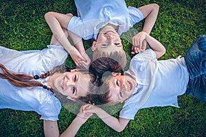 Young boys and girls lying on green grass