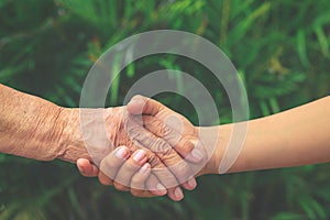 young boys hand holding old female hand