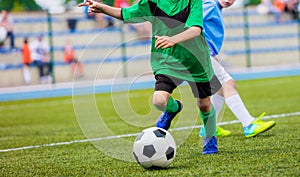 Young boys playing football game. Young players kicking soccer ball on sports grass pitch