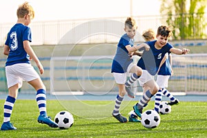 Young boys playing football training game. Happy children kicking soccer balls on practice pitch