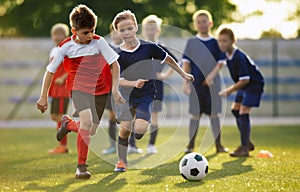 Young boys playing soccer training game. Junior football practice competition between players running in a duel and kicking ball