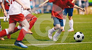 Young Boys in White and Red Soccer Jersey Shirts and Soccer Cleats Kicking Soccer Ball photo