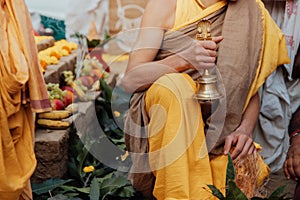 Young Brahman Brahmachari holds a bell in his hands during Yagya a fire flame ritual of hindu pooja performating during sacred