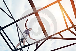 Young brave man balancing on the top of high metal bridge