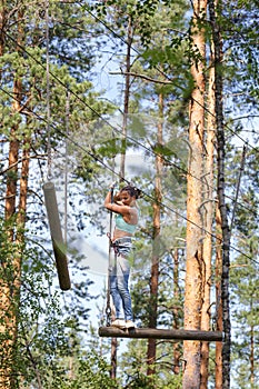 Young brave woman climbing in adventure rope park