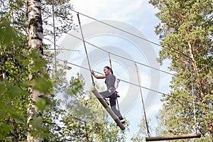 Young brave woman climbing in adventure rope park