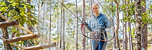 Young brave woman climbing in a adventure rope park BANNER, LONG FORMAT