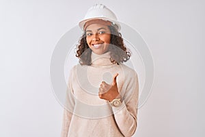 Young brazilian architect woman wearing security helmet over isolated white background doing happy thumbs up gesture with hand