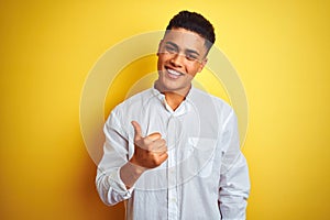 Young brazilian businessman wearing elegant shirt standing over isolated yellow background doing happy thumbs up gesture with hand