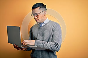 Young brazilian businessman working using laptop standing over isoltated yellow background with a confident expression on smart
