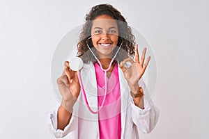 Young brazilian doctor woman using stethoscope standing over isolated white background doing ok sign with fingers, excellent