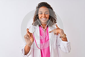 Young brazilian doctor woman using stethoscope standing over isolated white background with surprise face pointing finger to