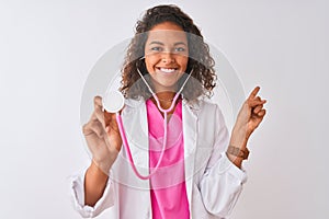 Young brazilian doctor woman using stethoscope standing over isolated white background very happy pointing with hand and finger to