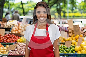 Young brazilian farmers market seller with apron selling fruits