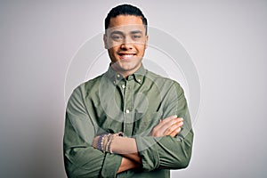 Young brazilian man wearing casual shirt standing over isolated white background happy face smiling with crossed arms looking at