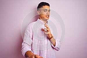 Young brazilian man wearing shirt standing over isolated pink background disgusted expression, displeased and fearful doing