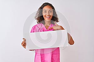 Young brazilian nurse woman holding banner standing over isolated white background with surprise face pointing finger to himself