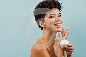 Young brazilian woman applying moisturizer