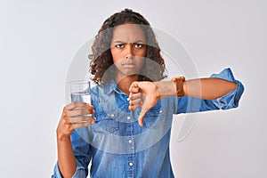 Young brazilian woman holding glass of water standing over isolated white background with angry face, negative sign showing