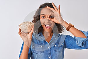 Young brazilian woman holding oat bowl standing over isolated white background with happy face smiling doing ok sign with hand on