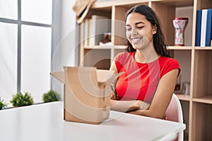 Young brazilian woman looking inside cardboard box happy face smiling with crossed arms looking at the camera