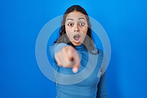Young brazilian woman standing over blue isolated background pointing displeased and frustrated to the camera, angry and furious
