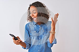 Young brazilian woman using smartphone standing over isolated white background very happy and excited, winner expression