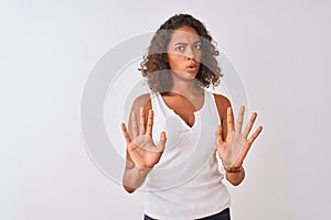 Young brazilian woman wearing casual t-shirt standing over isolated white background Moving away hands palms showing refusal and