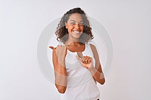 Young brazilian woman wearing casual t-shirt standing over isolated white background Pointing to the back behind with hand and