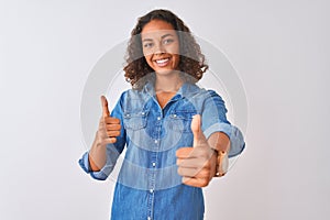 Young brazilian woman wearing denim shirt standing over isolated white background approving doing positive gesture with hand,